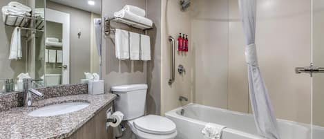 A modern bathroom with a marble sink, a toilet, a bathtub, and a shower.