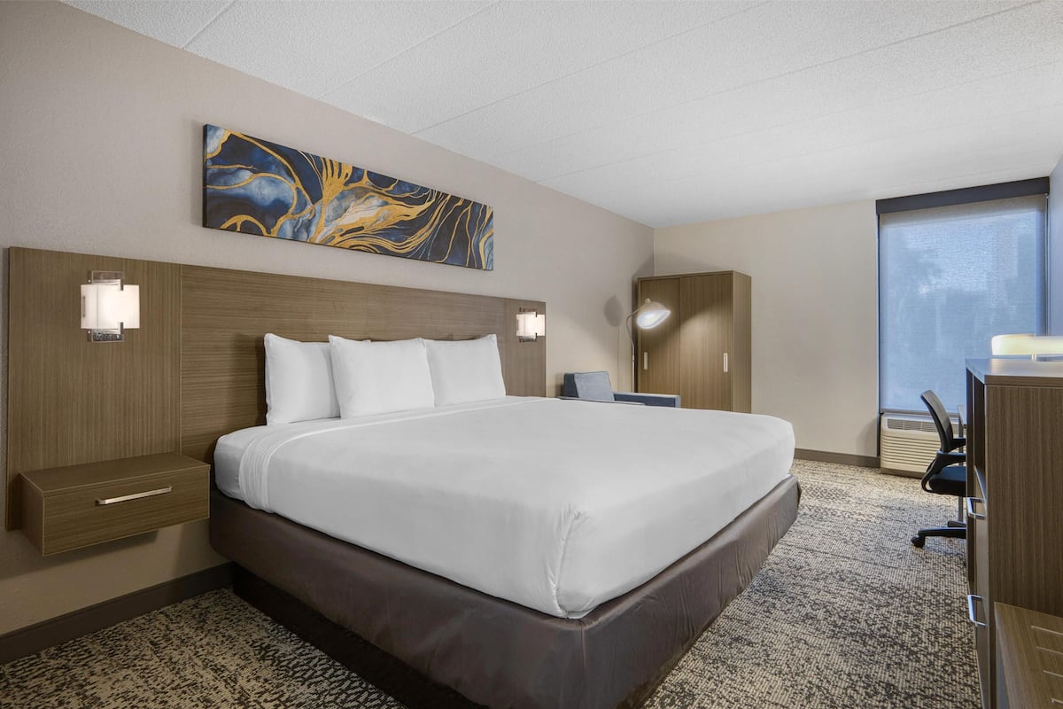 Een hotelkamer met een groot bed, nachtlampjes, een bureau en een raam.