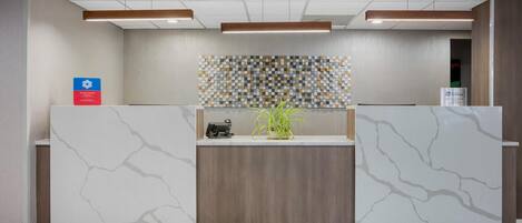 Un área de recepción con un mostrador de diseño marmolado, pared revestida de paneles de madera y un diseño de mosaico sobre el mostrador.