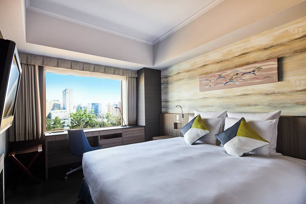 Une chambre d’hôtel avec un grand lit, un bureau et une vue sur la ville.