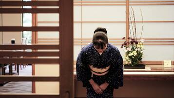 Un interior japonés tradicional con suelo de tatami, puerta corrediza de madera y un arreglo floral.