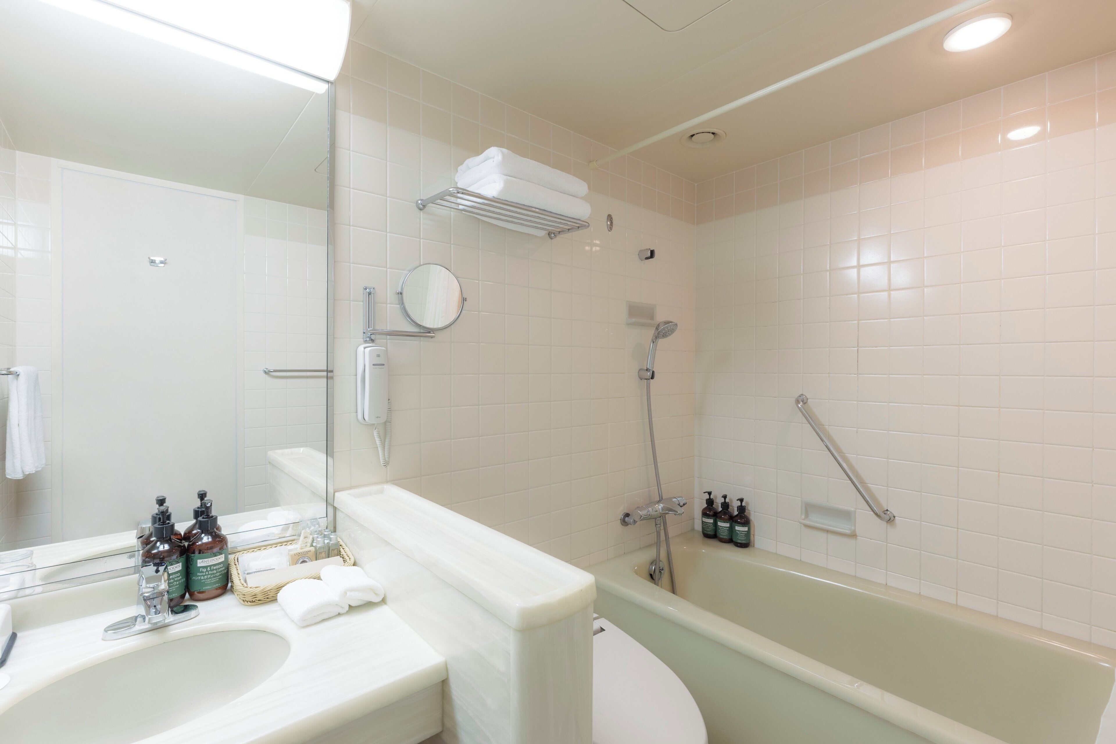 Een badkamer met een wastafel, spiegel, toilet en bad.