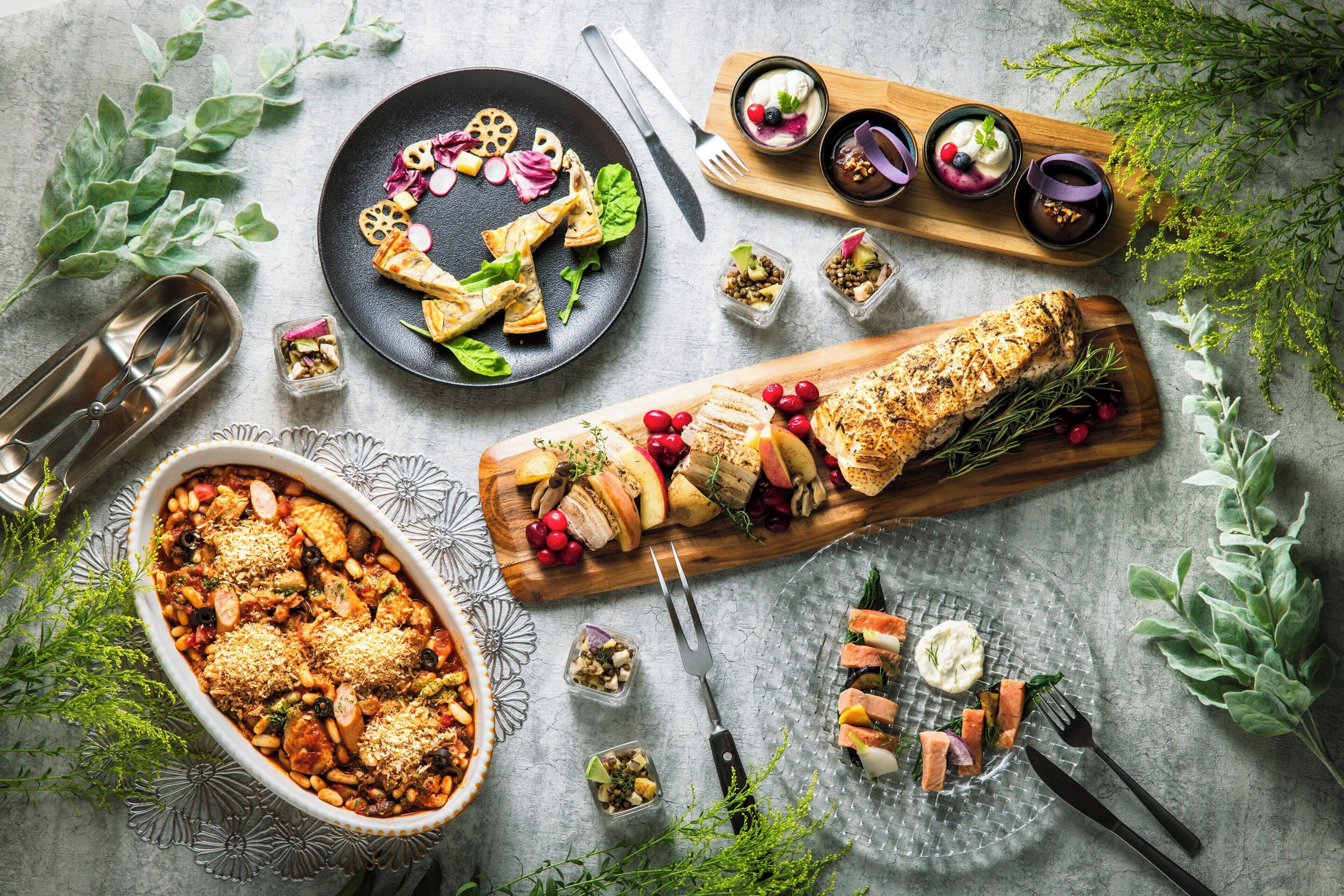 A variety of dishes including a baked casserole, a charcuterie board, and several small bowls of dips and garnishes.