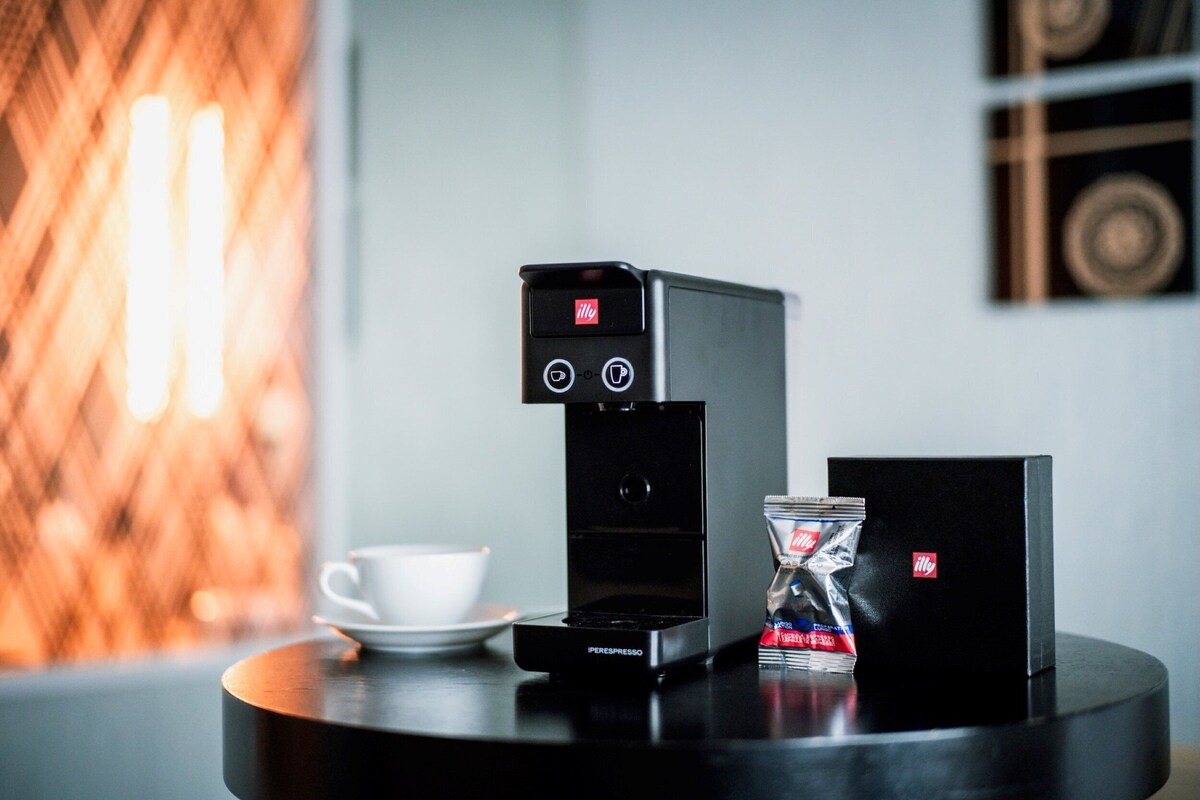 Une machine à café, une tasse et un paquet de café sur une table.