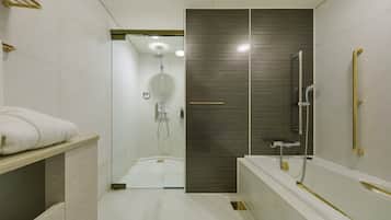 Un baño moderno con ducha de vidrio, bañera con detalles dorados y un perchero para toallas.