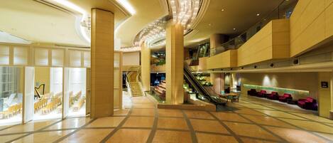 A spacious lobby with a central staircase, seating areas, and a modern design.