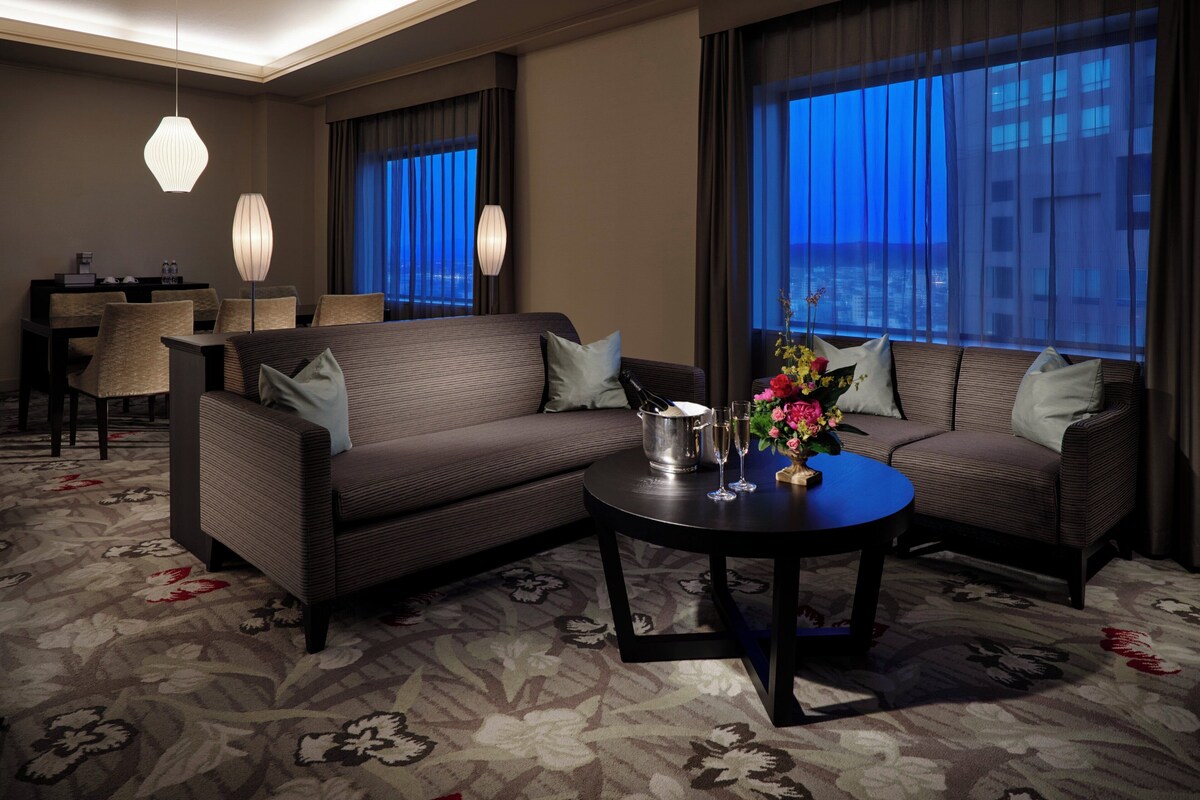 Une chambre d’hôtel comprenant un canapé, une table à manger et une table basse avec un vase.