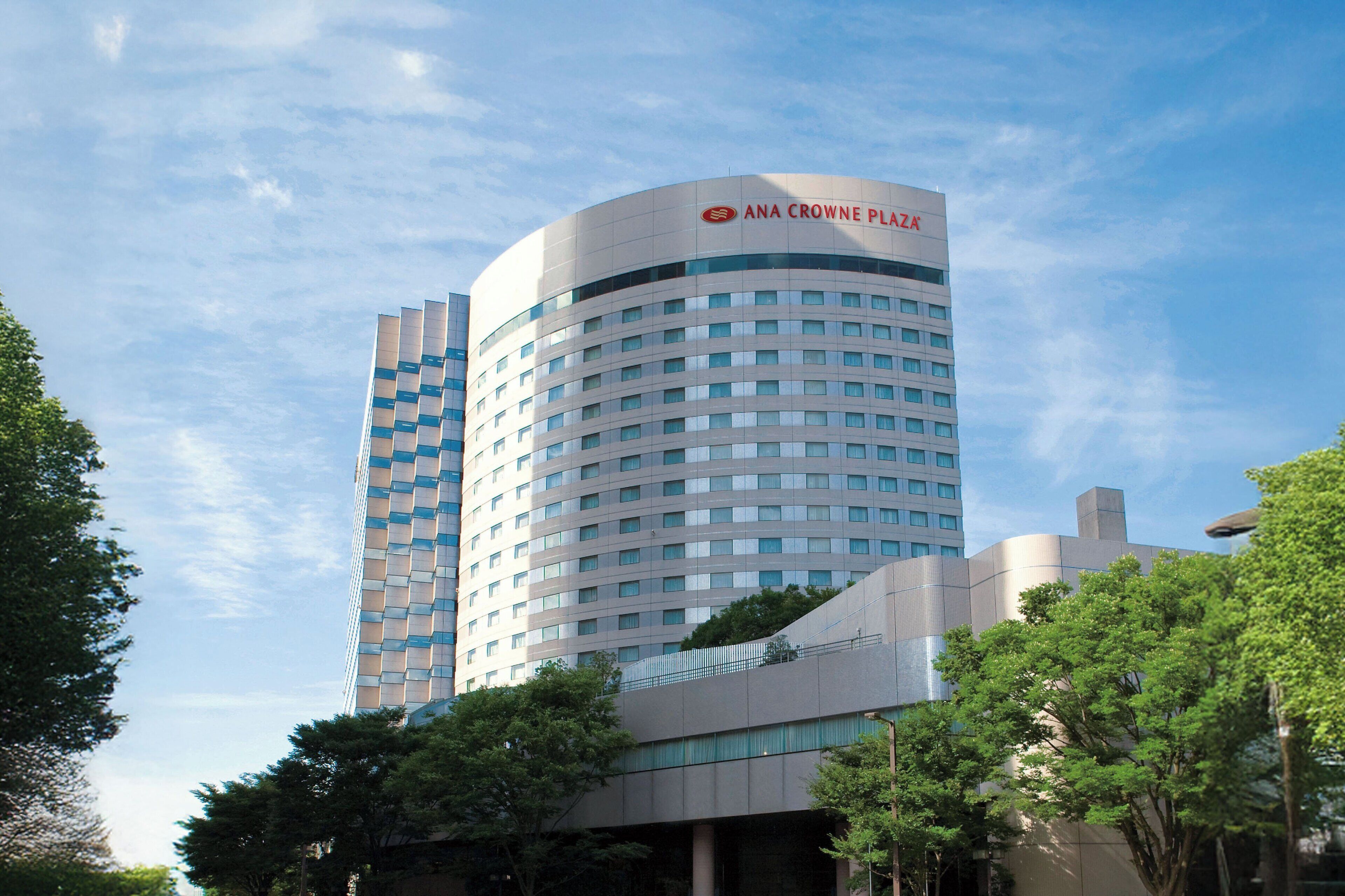 Een modern hotel met een gebogen gevel, meerdere verdiepingen en een opvallend logo bovenaan.