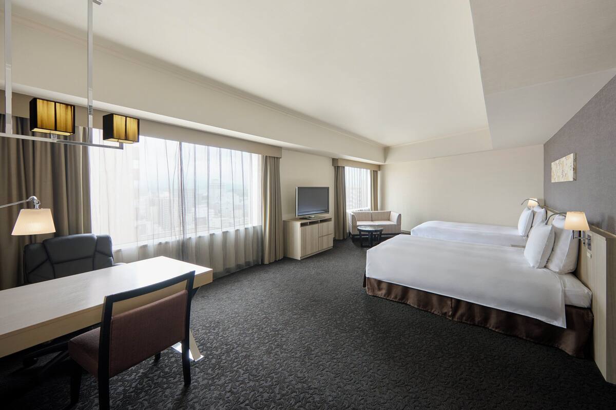 Une chambre d’hôtel équipée d’un lit, d’un bureau, d’une chaise, d’une télévision et d’un canapé.