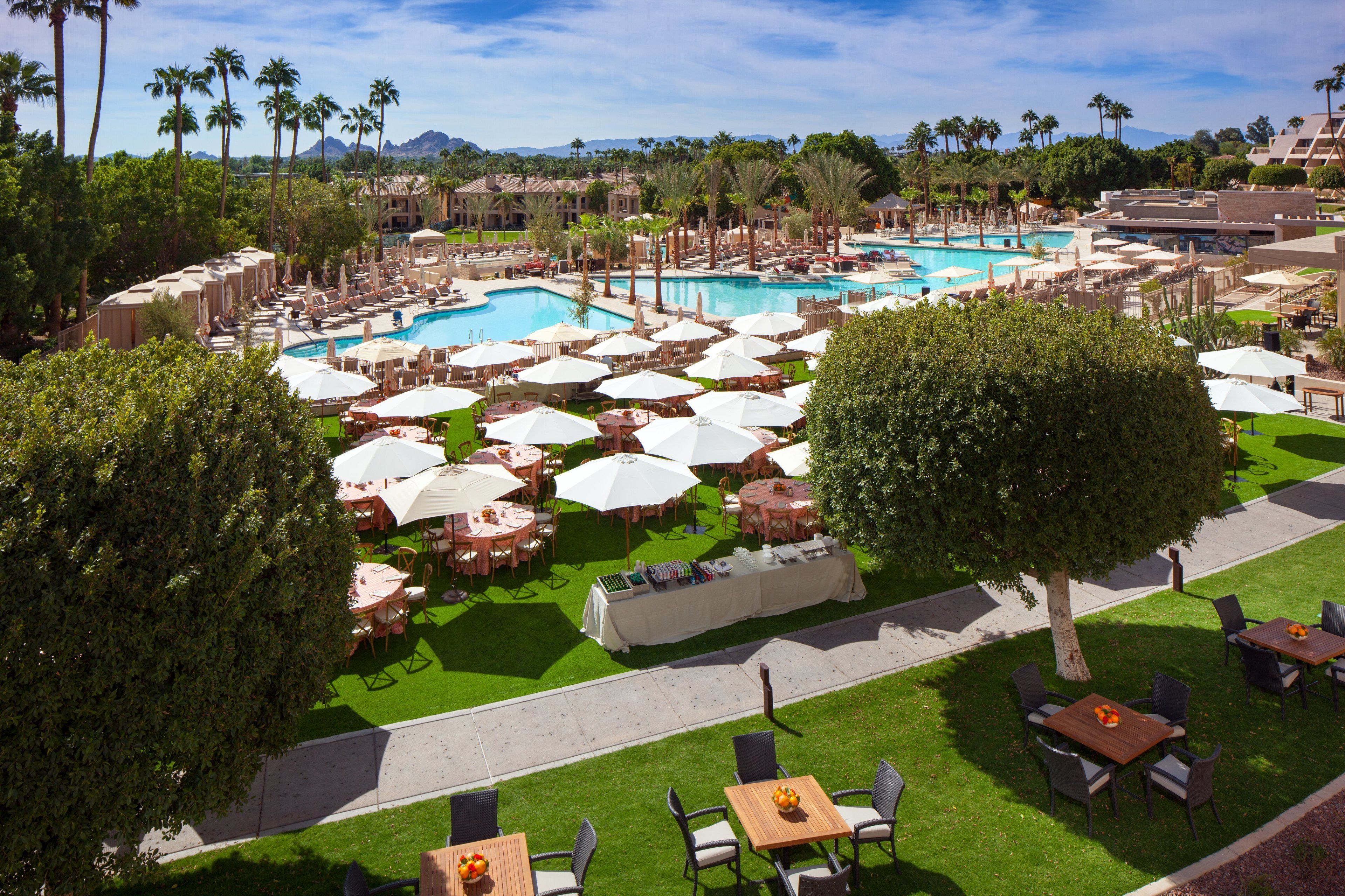 Un resort con varias piscinas, zonas de comedor al aire libre y abundante vegetación.