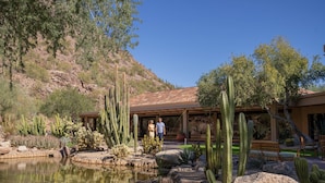 A desert landscape with a pond, cacti, and a building with a tiled roof. - The Phoenician, a Luxury Collection Resort, Scottsdale (Paradise Valley)