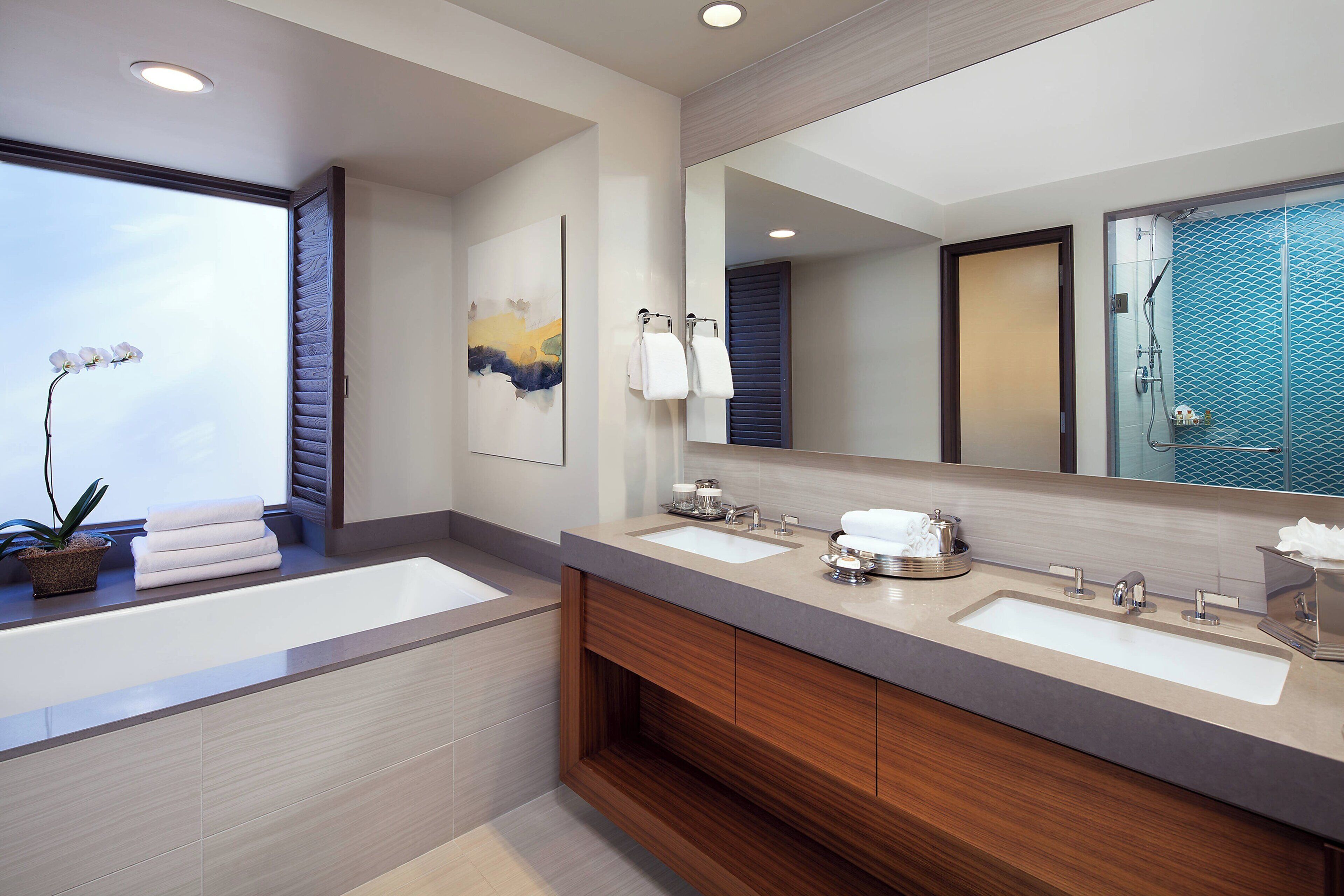 A modern bathroom with two sinks, a large mirror, and a potted orchid.