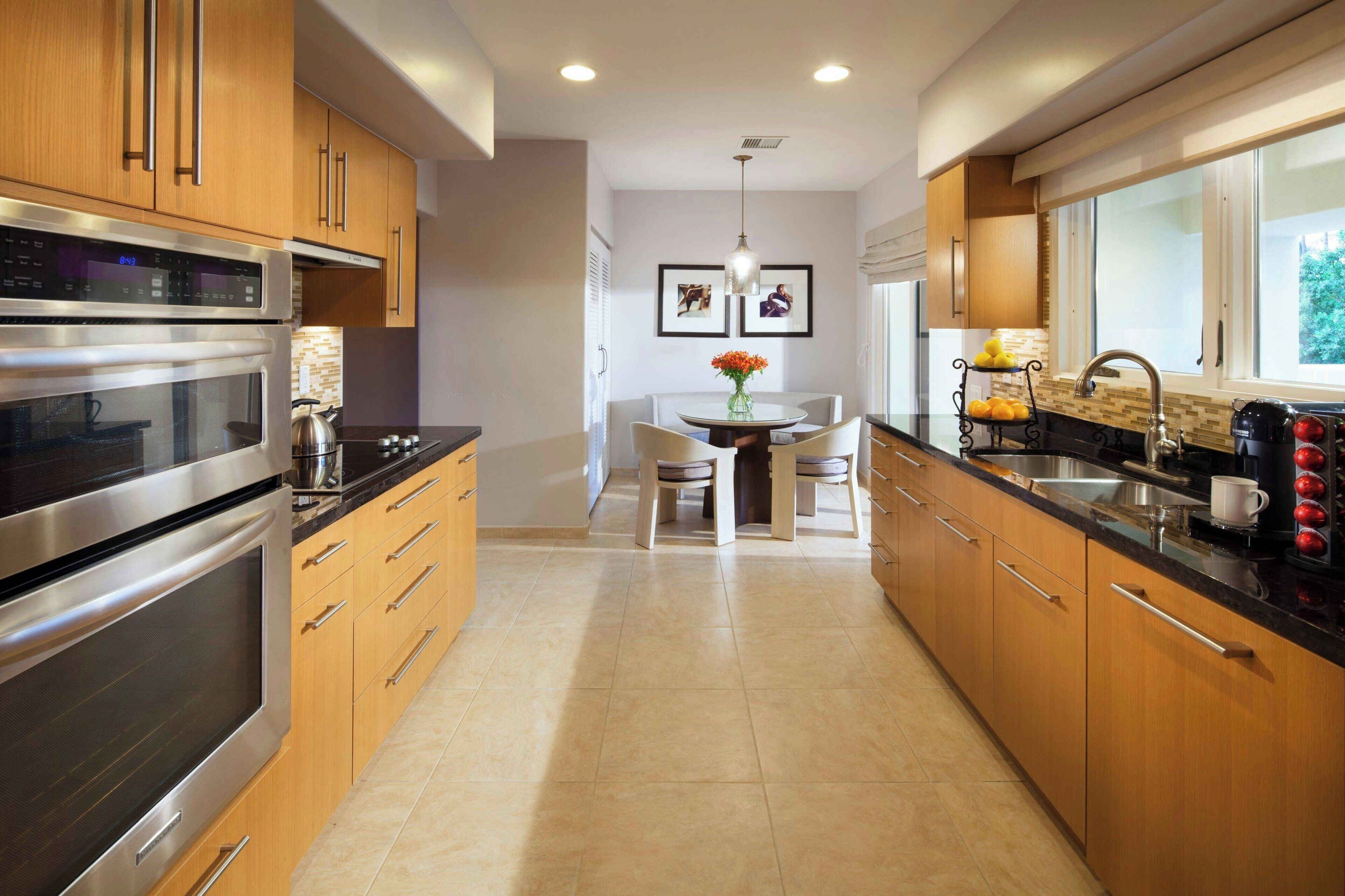 Una cocina moderna con electrodomésticos de acero inoxidable, armarios de madera y una zona de comedor con mesa y sillas.