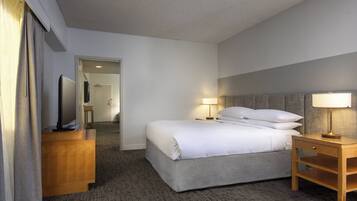 A hotel room with a bed, bedside tables, a TV, and a lamp.