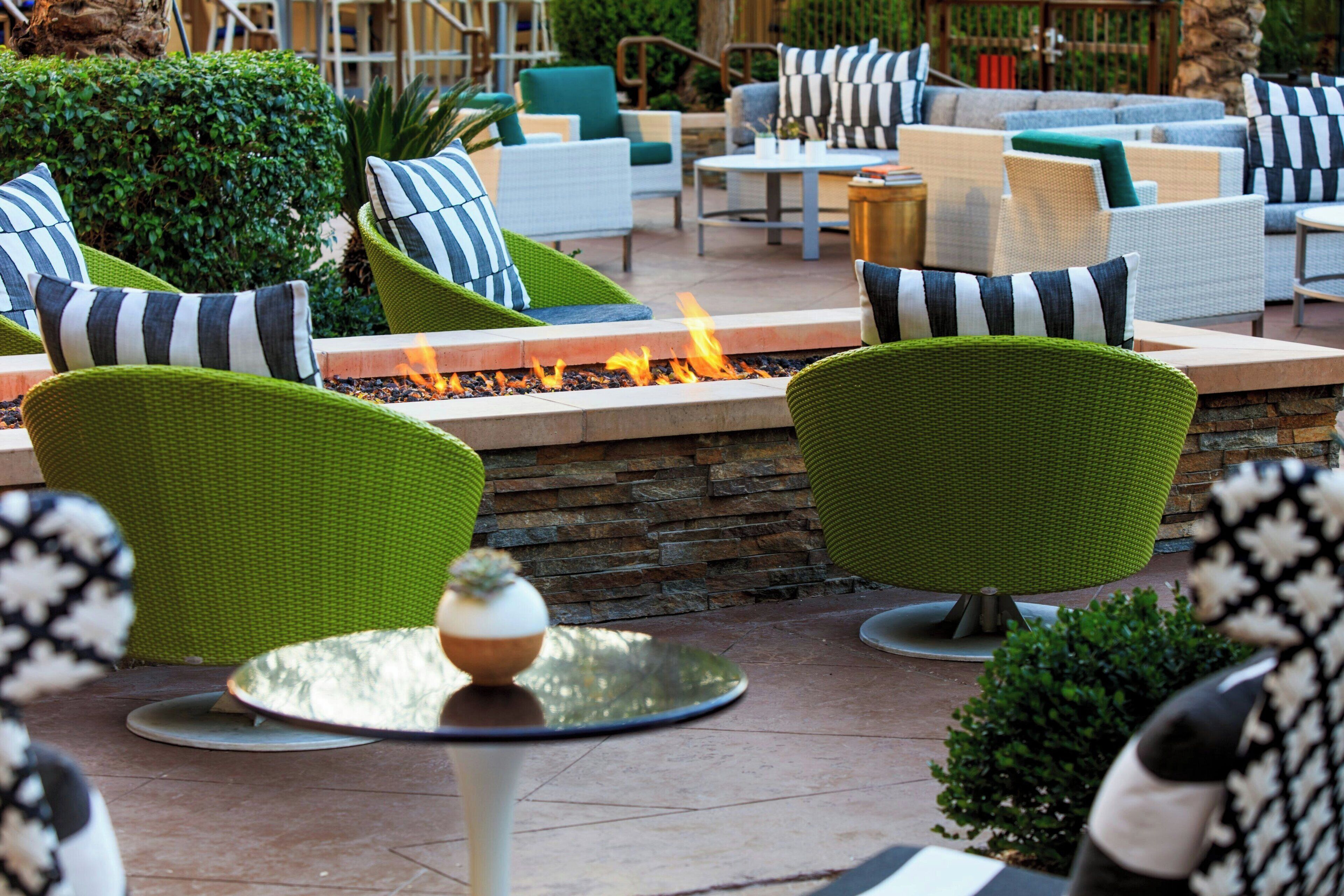 A patio area with wicker furniture, a fire feature, and a stone wall.