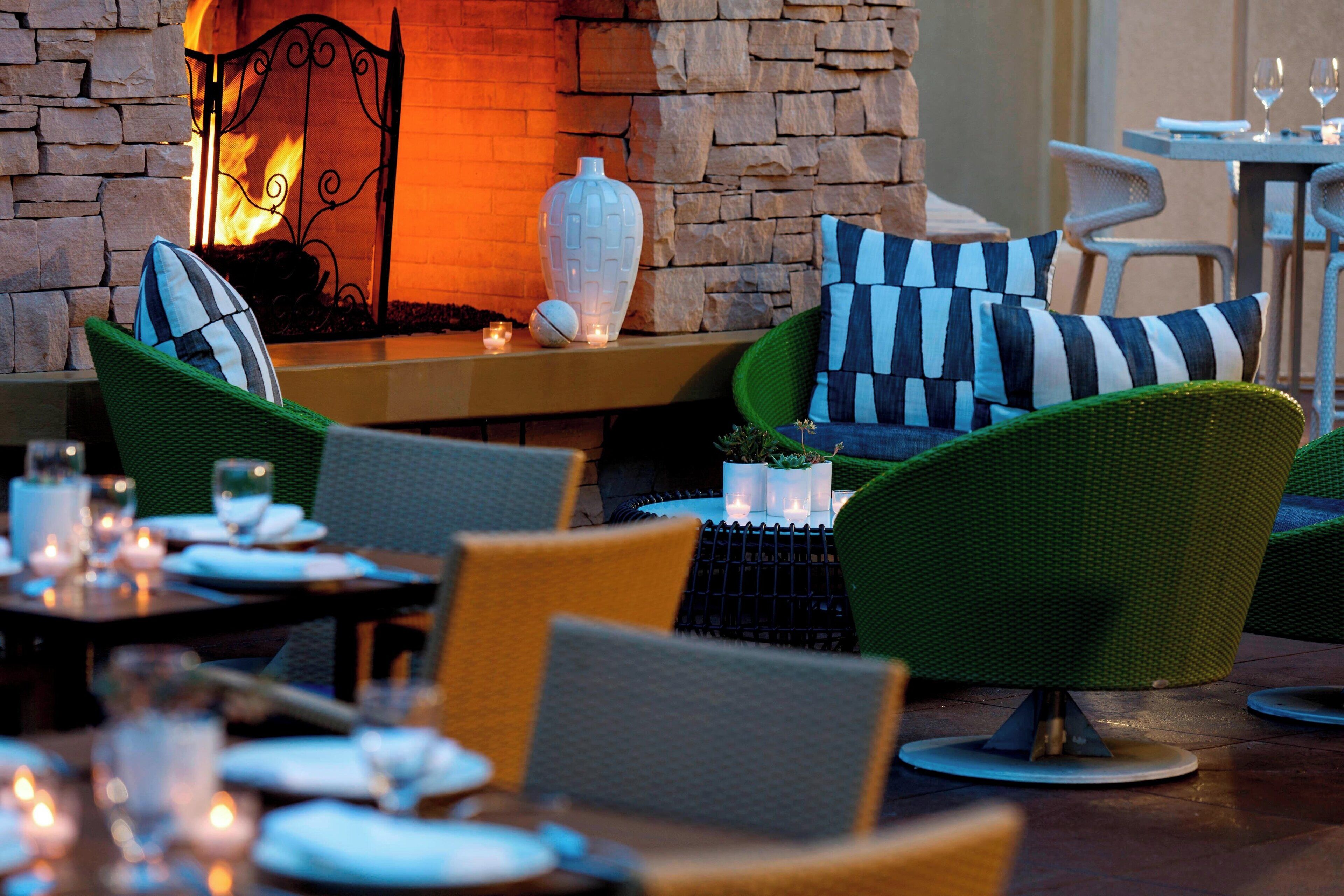 A cozy outdoor seating area with wicker chairs and a stone fireplace.