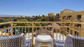 Enjoy the serene pool view from this balcony with comfortable wicker furniture.