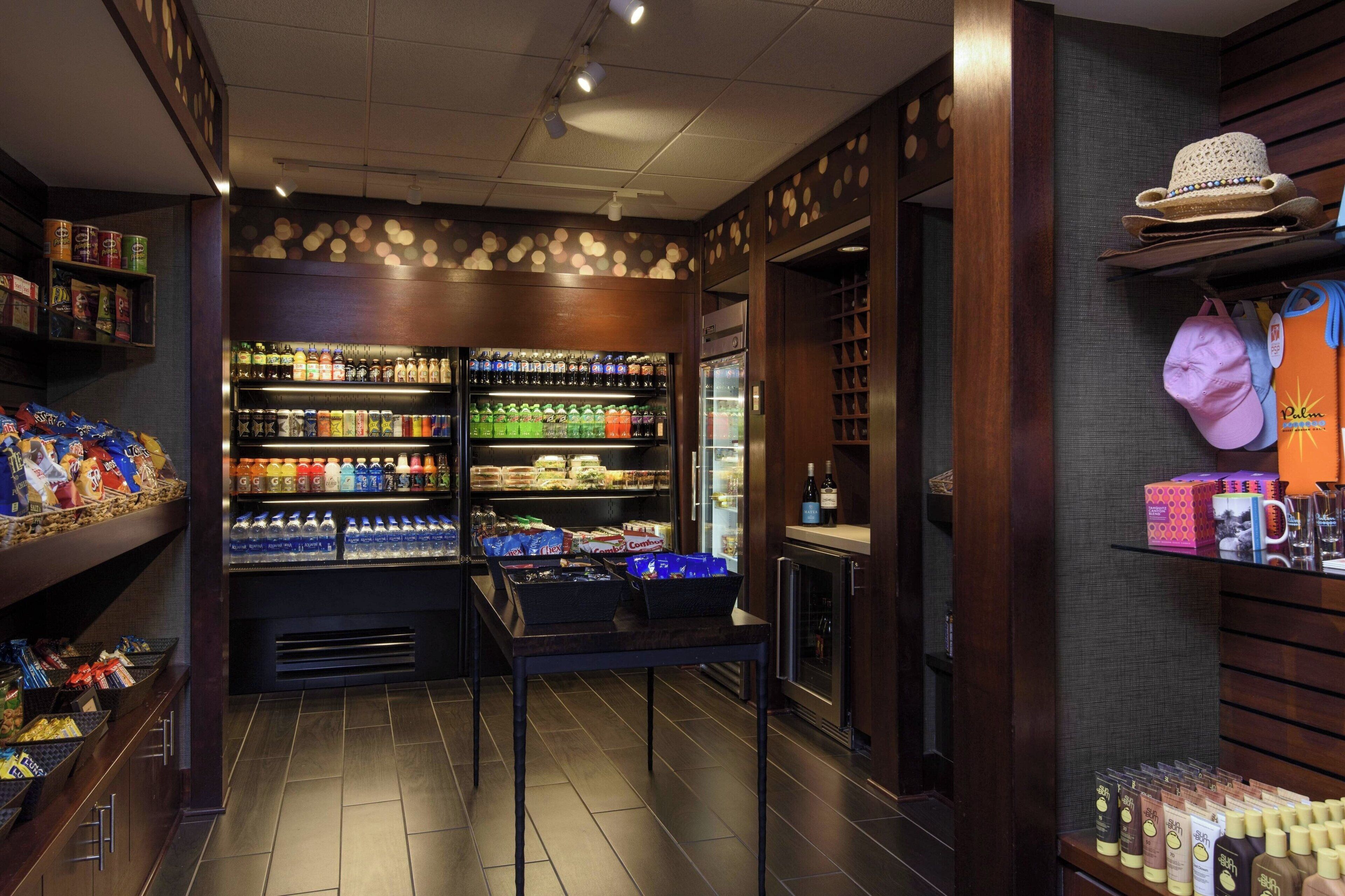 Un bar bien approvisionné en boissons et en en-cas, avec des étagères remplies de boissons et de collations, un réfrigérateur et une table avec des paniers.