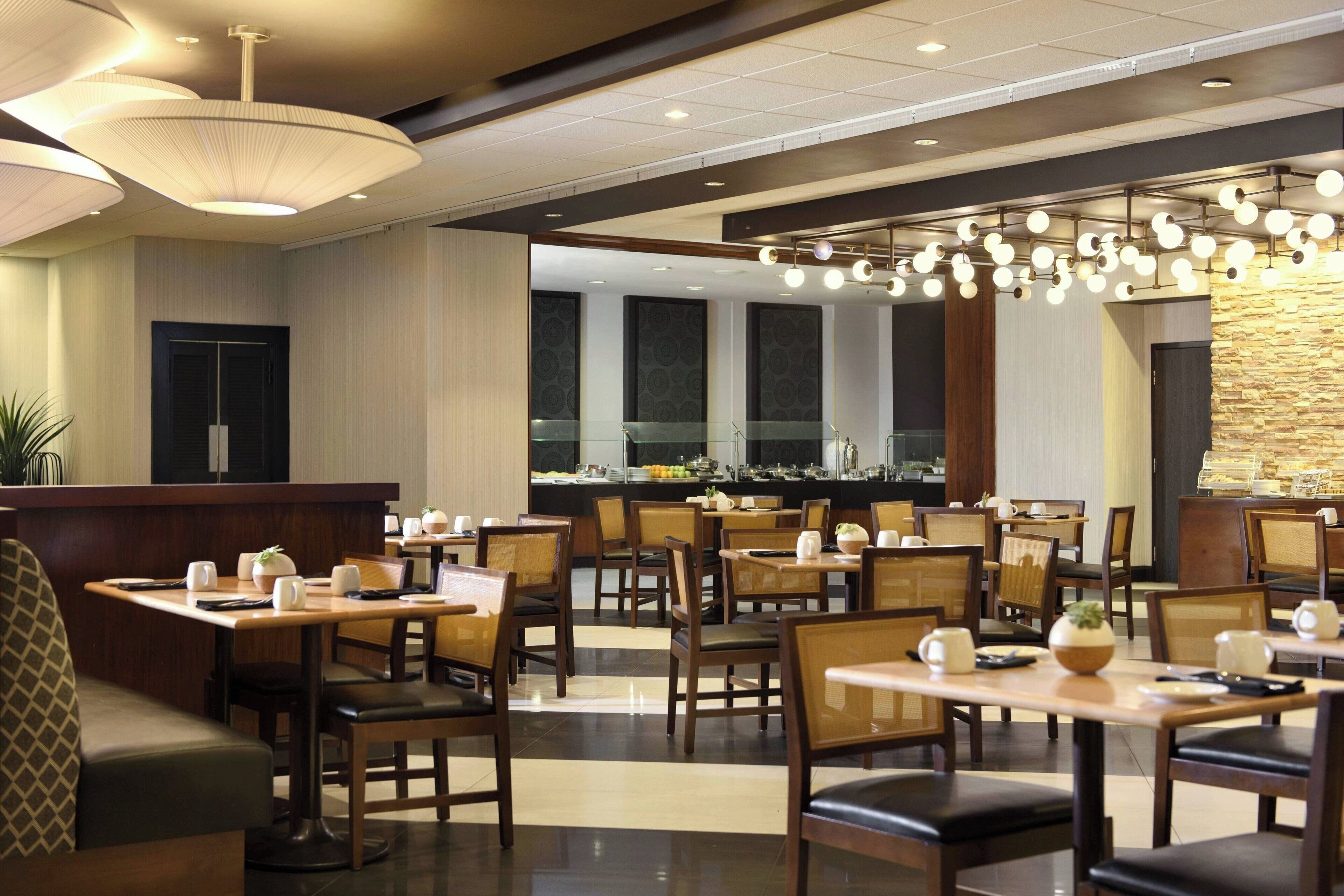 A restaurant with multiple tables and chairs, a counter, and a decorative ceiling light fixture.