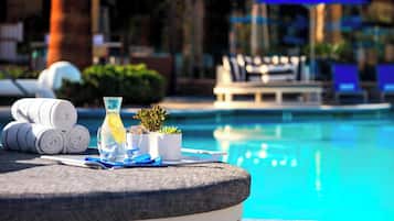A poolside setting with a table set for a drink, towels, and a small plant.