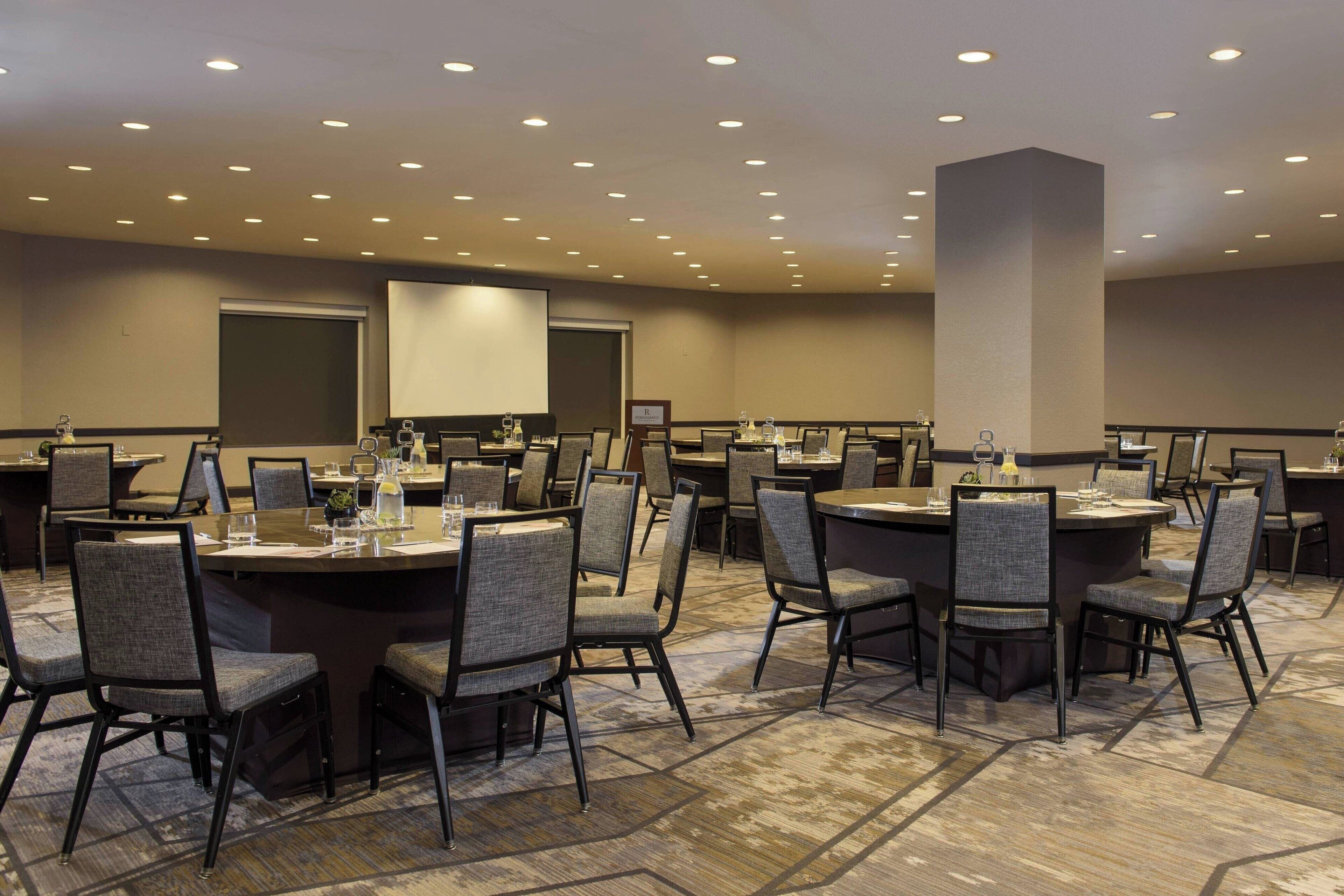 A conference room with multiple tables and chairs, equipped with nameplates and water bottles.