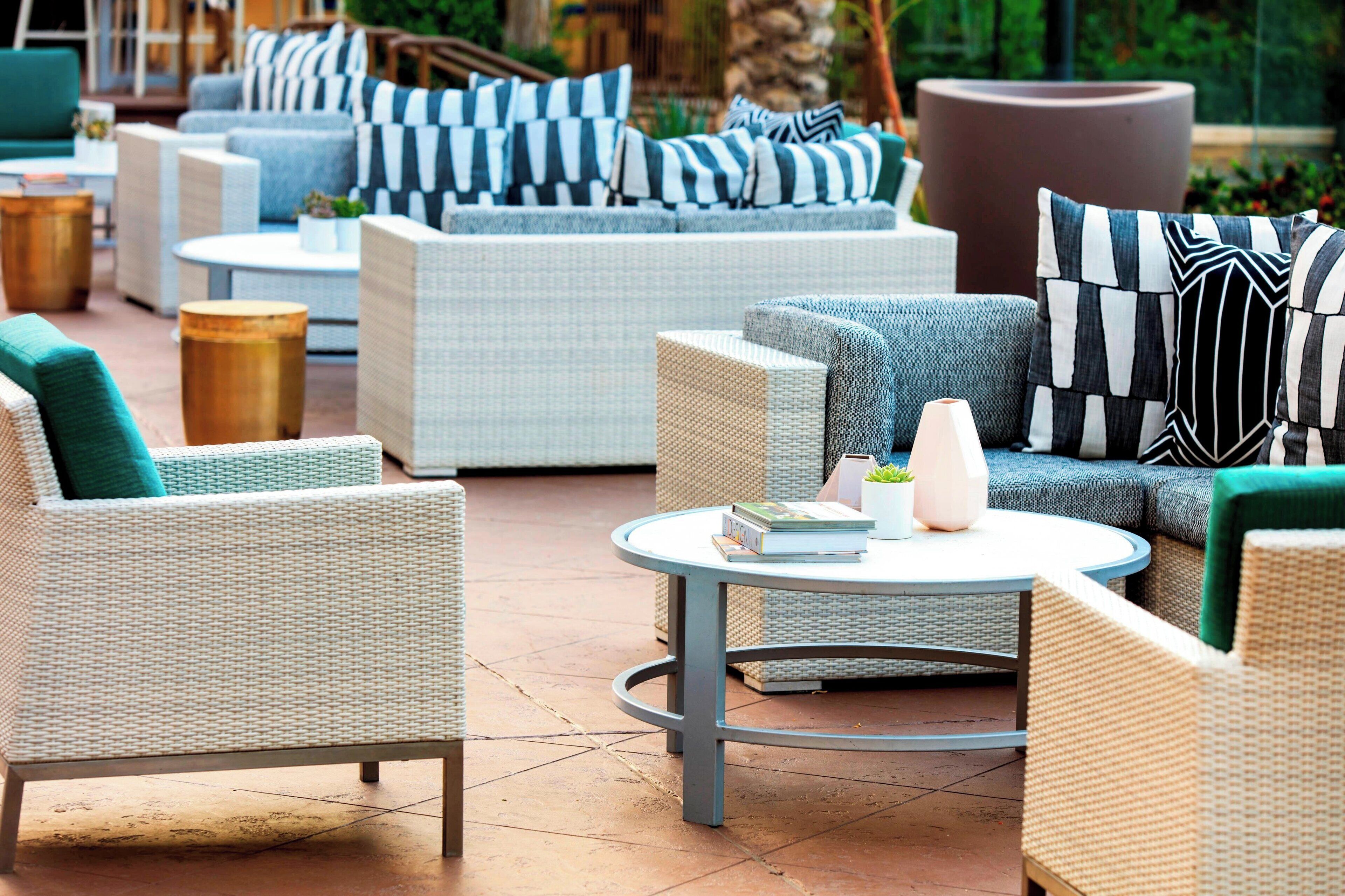 A patio area with wicker furniture, including sofas and chairs, arranged around a central round table.