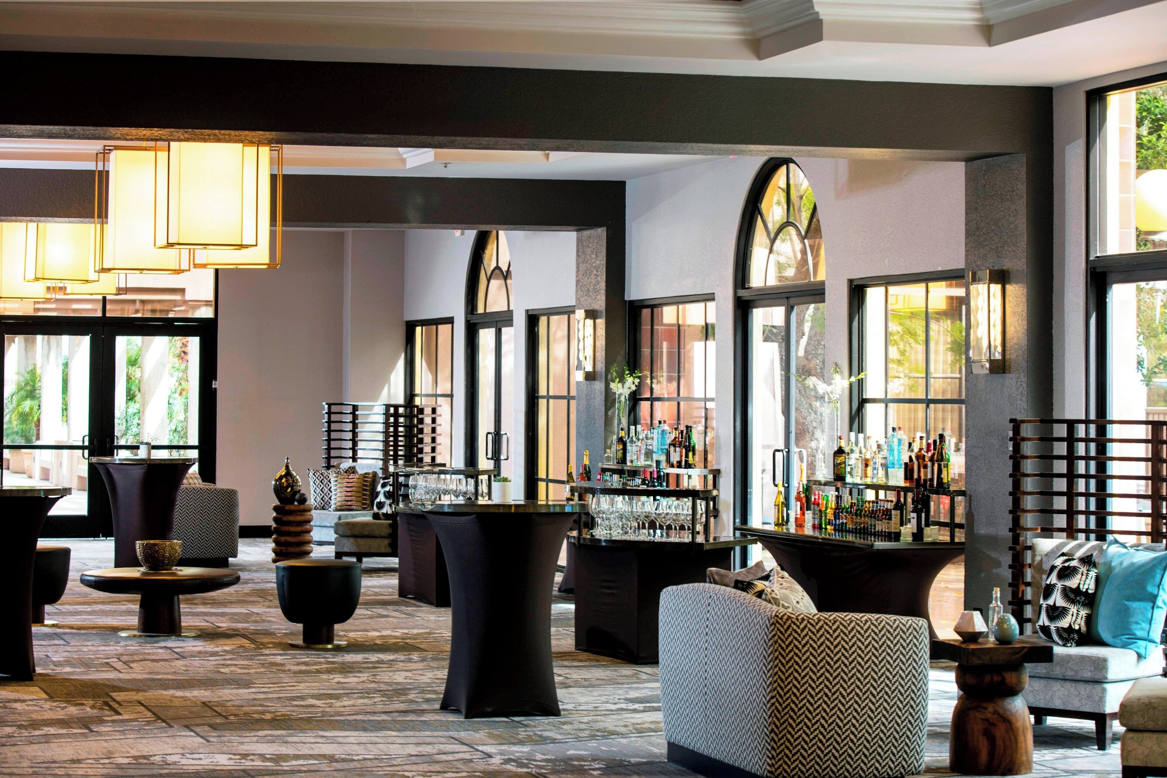 A spacious lobby with a bar area, seating arrangements, and large windows allowing natural light.