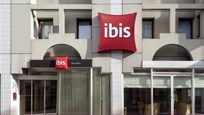 A hotel with a prominent red 'ibis' sign, a glass entrance, and a 'Pau Centre' sign. - ibis Pau Centre (Pau)