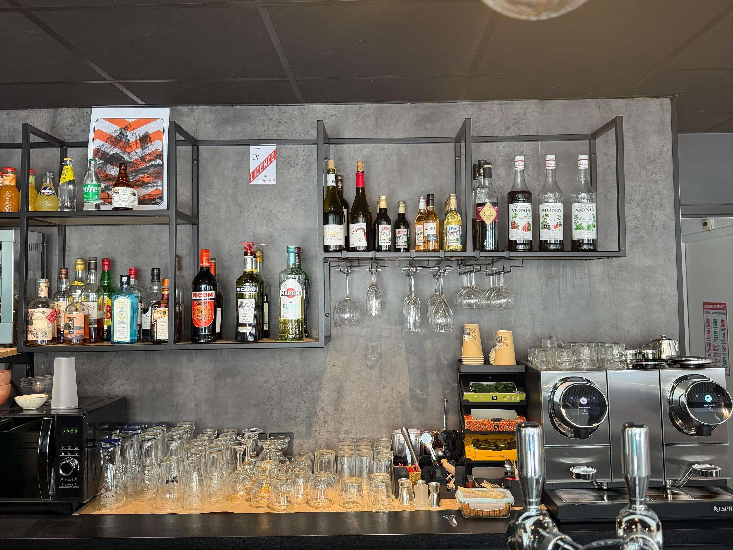 A bar area with shelves of liquor bottles, glasses, and a coffee machine.