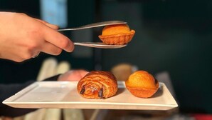 A hand holding a spoon over a plate with pastries. - ibis Pau Centre (Pau)