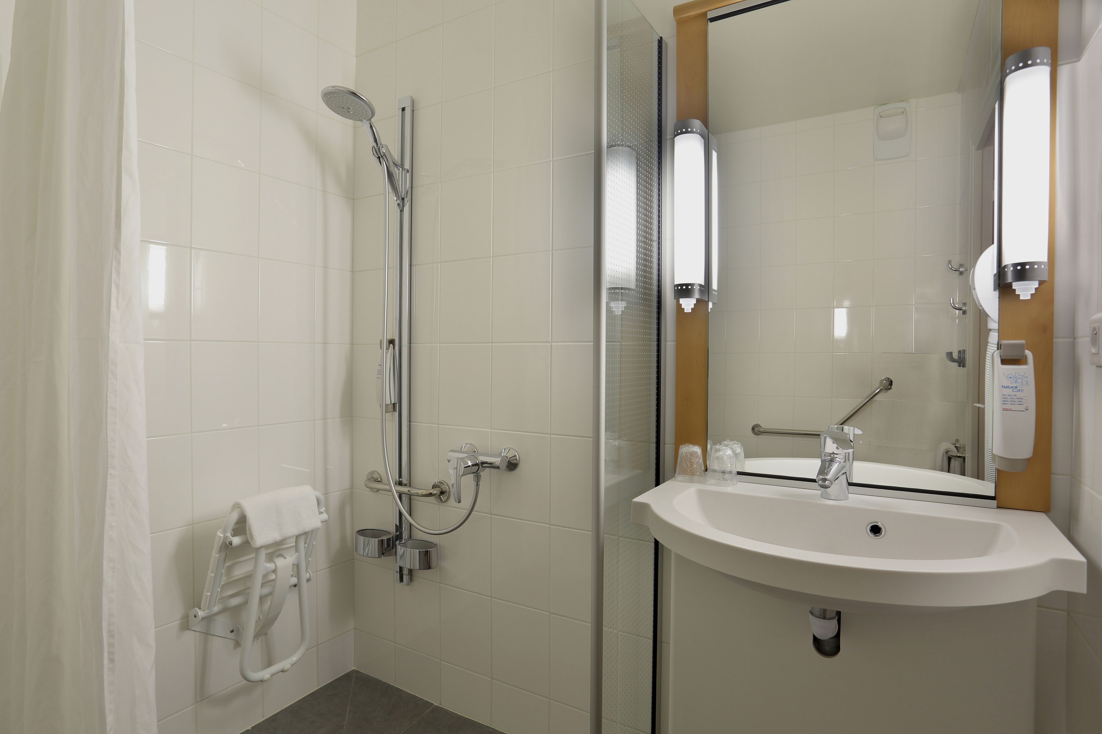 A modern bathroom with a glass-enclosed shower, a white sink, and a towel rack.