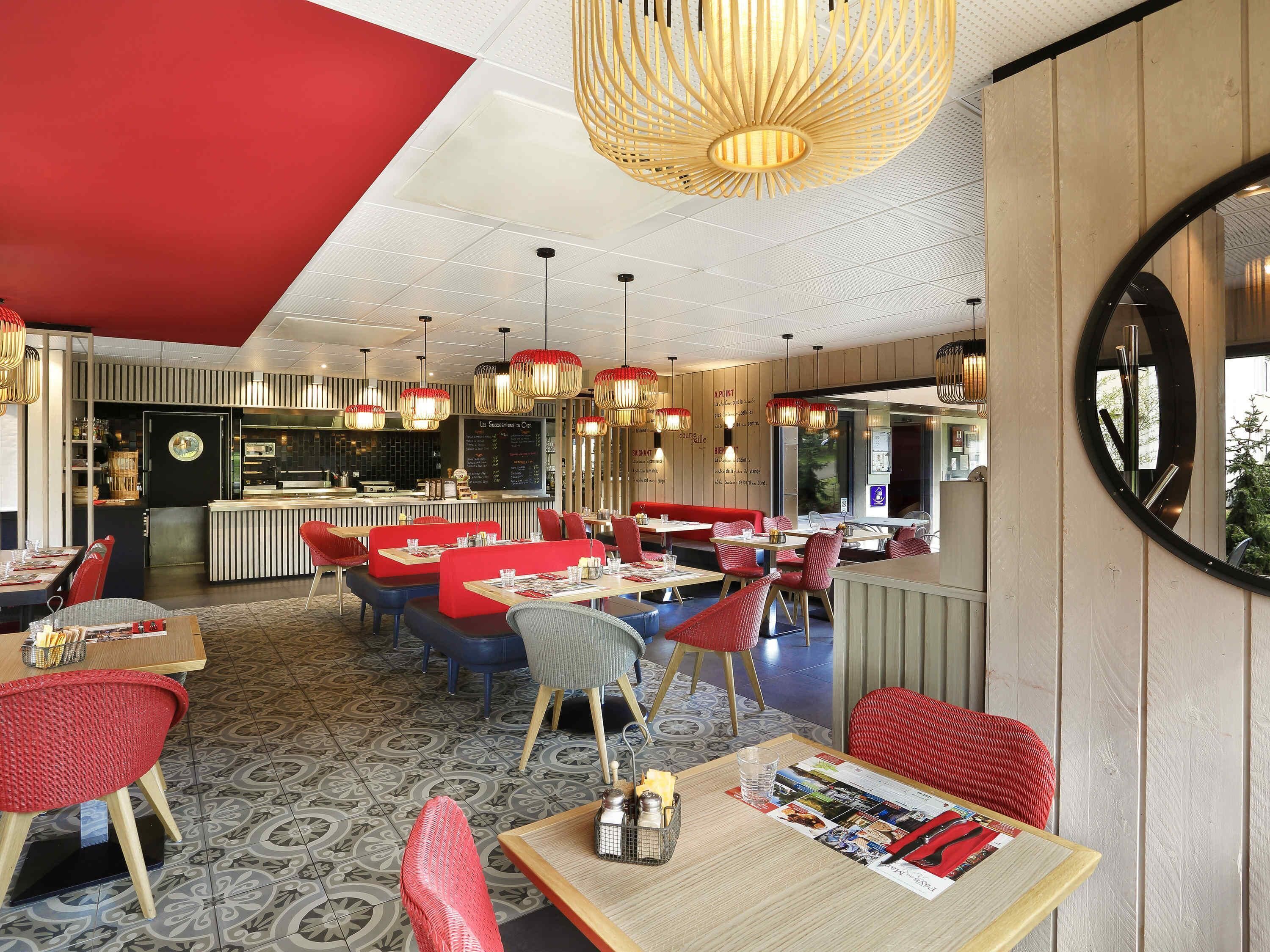 A restaurant interior with red and blue seating, a bar area, and a menu board.