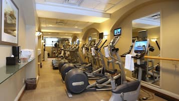Un gimnasio con equipo de ejercicio, una zona de recepción y un espejo que refleja el equipo.