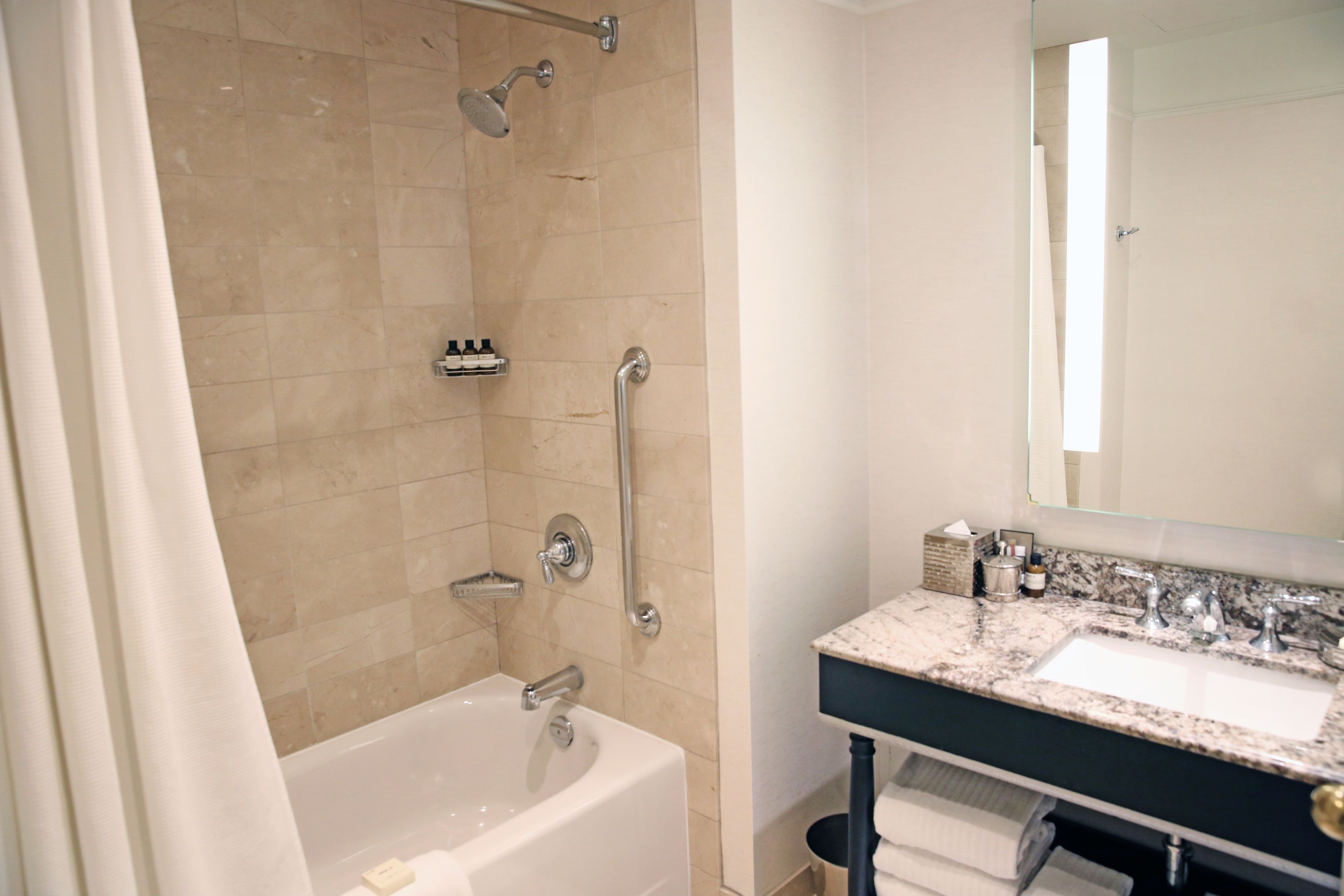 Un baño moderno con bañera, ducha, tocador con lavabo y espejo.