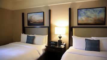 A hotel room with two beds, a nightstand with a lamp, and two framed pictures on the walls.