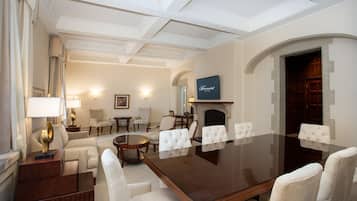 Une salle de conférence équipée d’une grande table, de chaises blanches, d’une cheminée et d’un écran de télévision.