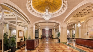 Un vestíbulo imponente con suelo a cuadros, un gran candelabro y arquitectura clásica.