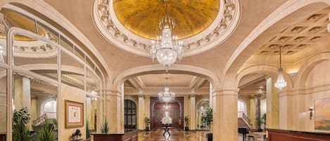 En storslagen entréhall med ett rutmönstrat golv, en stor kristallkrona och klassisk arkitektur.