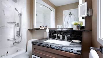 A modern bathroom with a marble sink, a bathtub, a shower, and a vanity with a mirror.