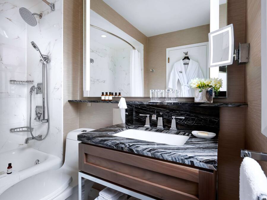 A modern bathroom with a marble sink, a bathtub, a shower, and a vanity with a mirror.