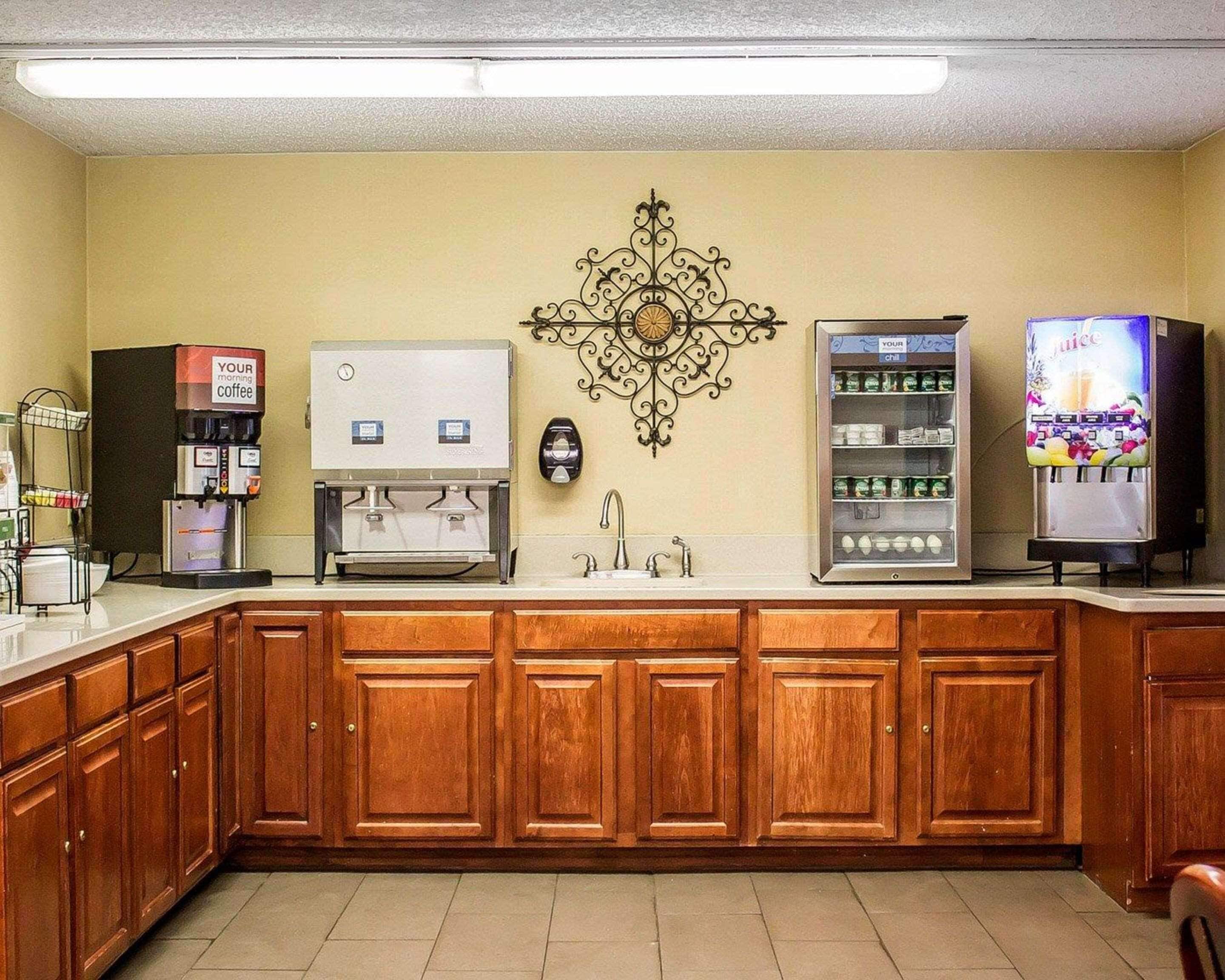 Una cocina con armarios de madera, una cafetera, un dispensador de jugo y un refrigerador.