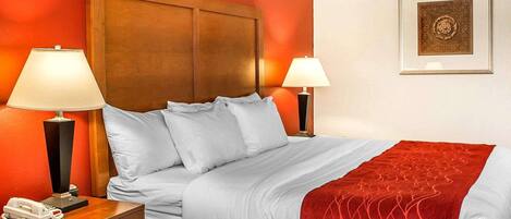 Ein Hotelzimmer mit einem großen Bett, zwei Nachttischlampen, einem Telefon und einem gerahmten Bild an der Wand.
