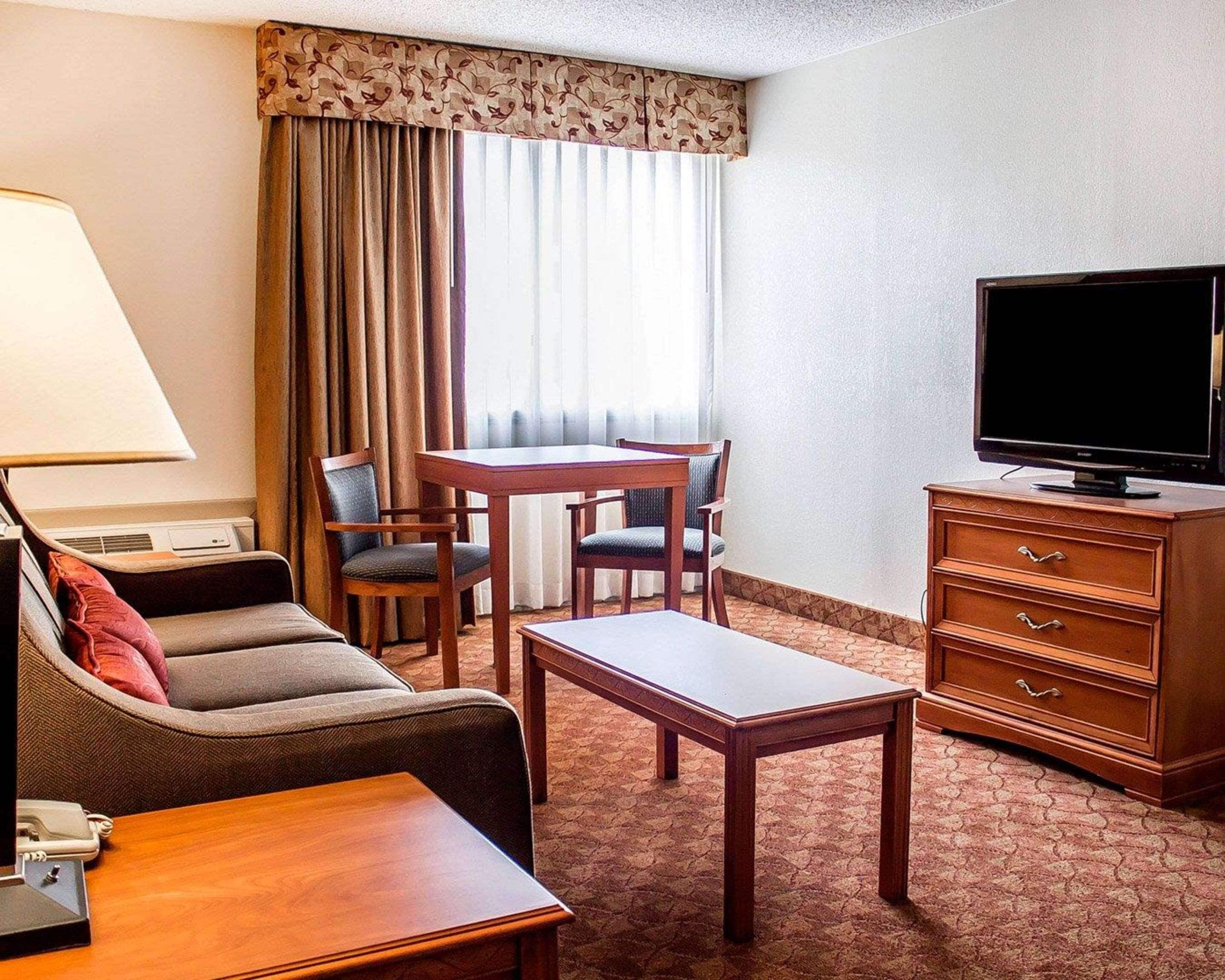 Une chambre d’hôtel avec un canapé, une petite table, un téléviseur, un bureau et une chaise.