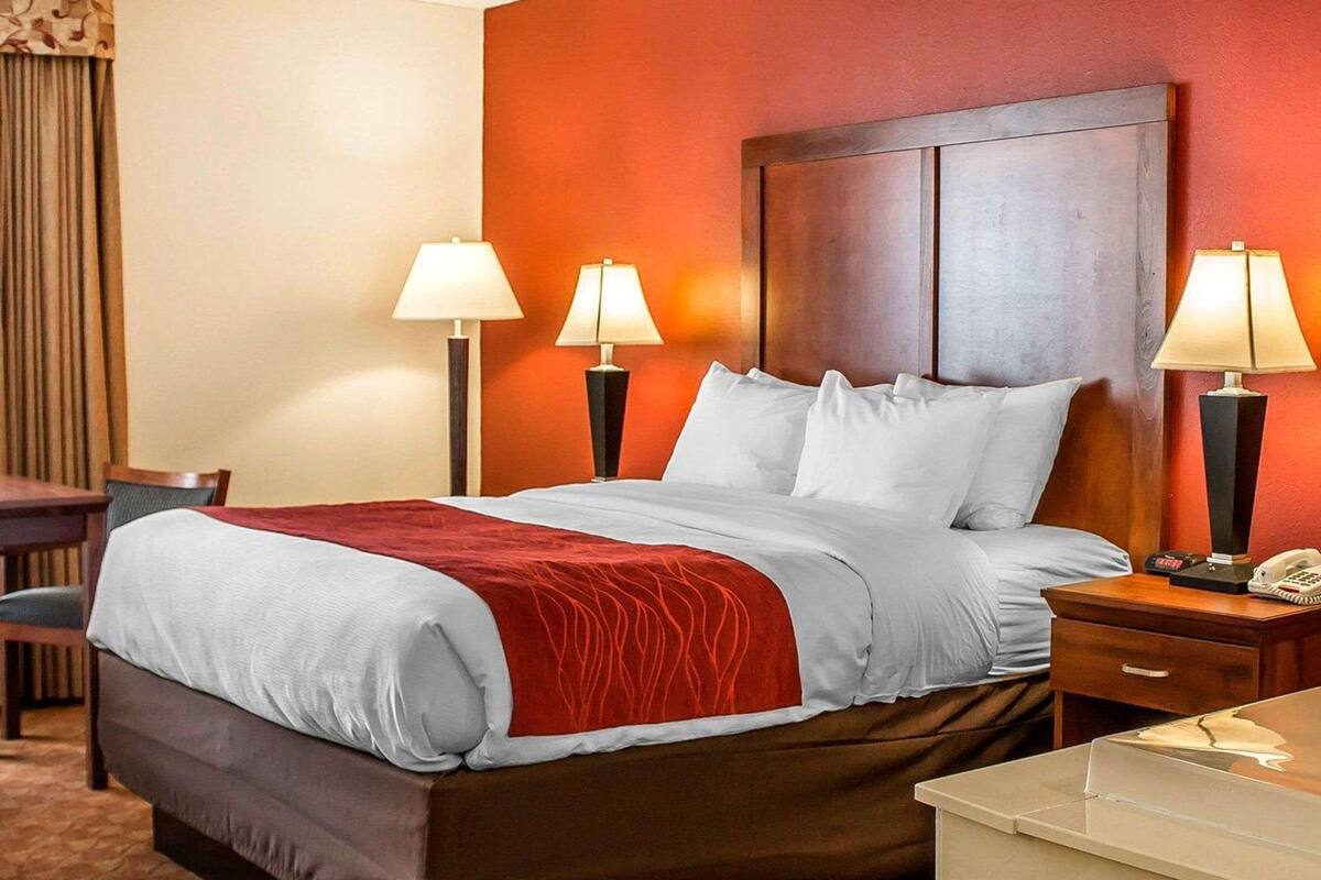 Una habitación de hotel con una cama grande, dos lámparas de noche, un escritorio y una silla.