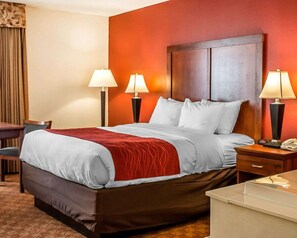 A hotel room with a large bed, two bedside lamps, a desk, and a chair.