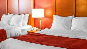 Hotellihuone, jossa on kaksi sänkyä, yöpöytä lampun kanssa ja puhelin.