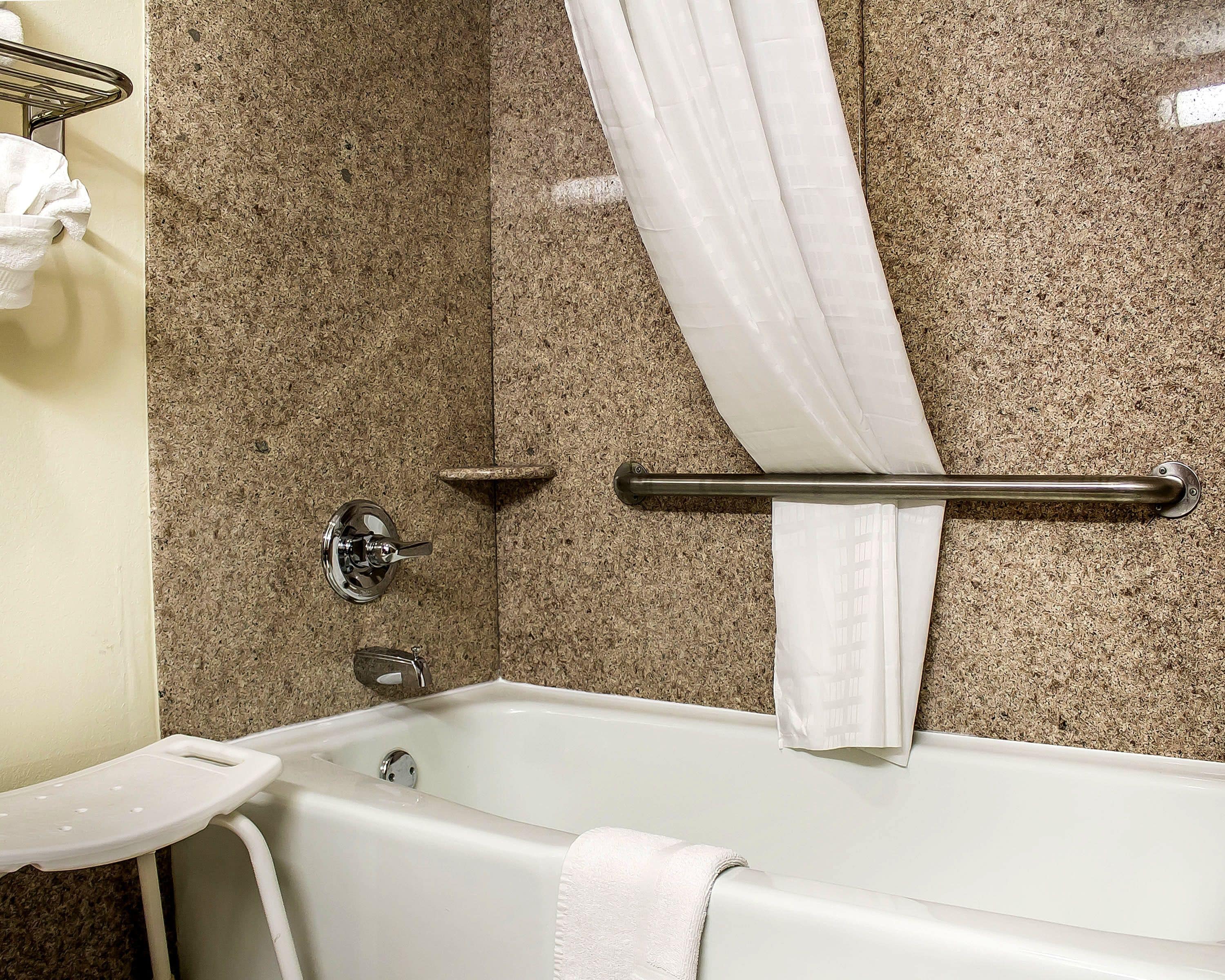 A bathroom with a bathtub, a shower curtain, and a towel rack.