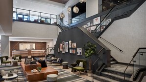 A spacious lobby with a modern staircase, comfortable seating areas, and a reception desk.