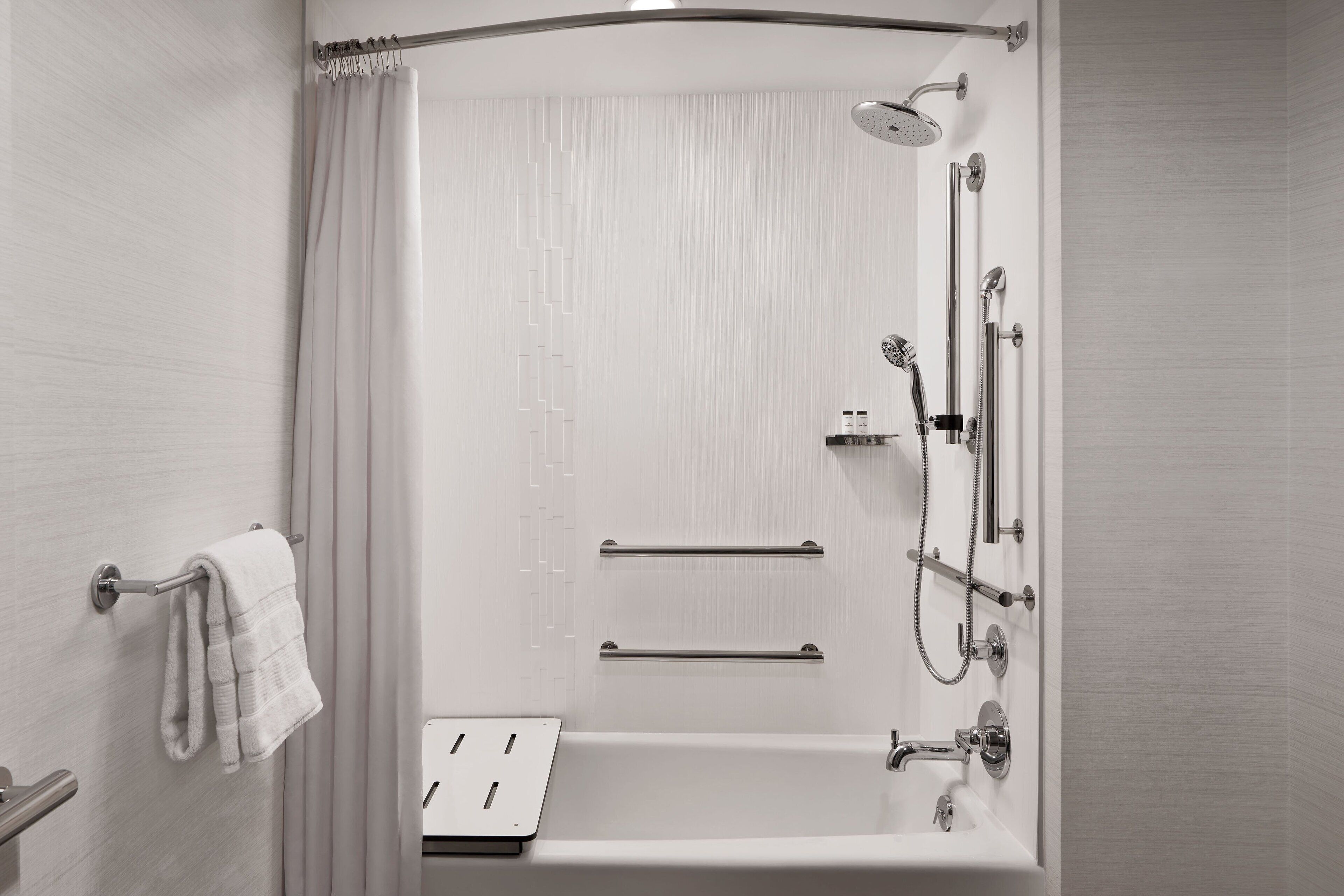 A modern bathroom with a walk-in shower, a bathtub, and a towel rack.