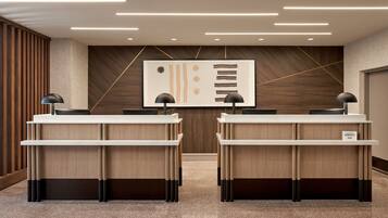 A reception area with two desks, a modern wall art piece, and a wooden panel design on the wall.